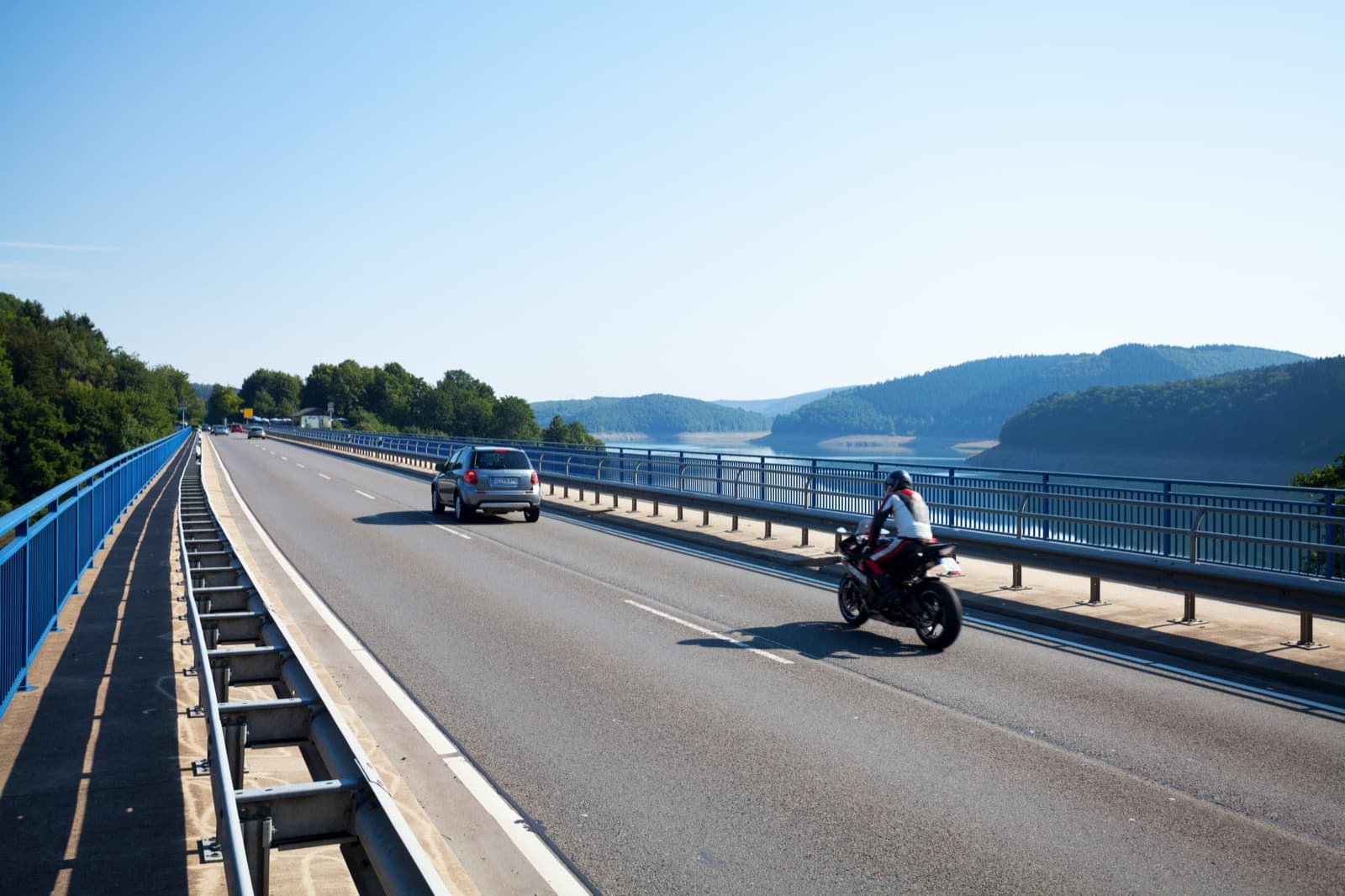 Auto und Motorrad auf einer Brücke über einen Stausee im Sauerland
